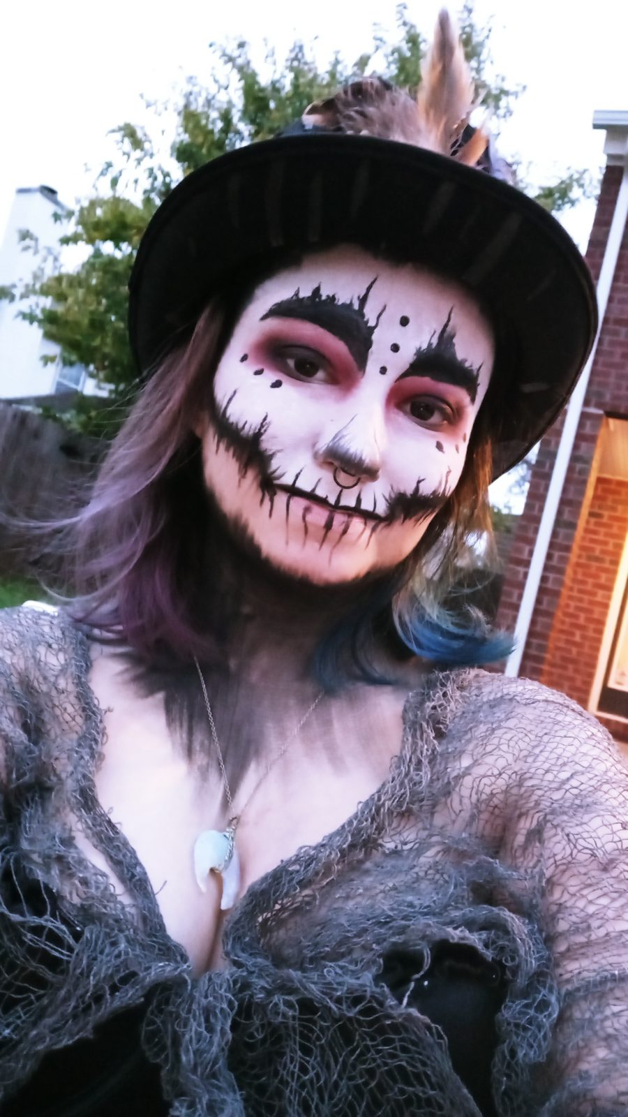 Grinning Moon — Full-face character paint — stitched smile, blackened eyes.